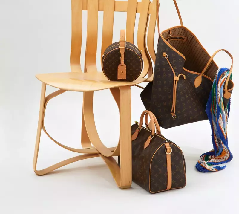 Wooden chair with fabulous Louis Vuitton handbags hanging on it's back and arm rest.